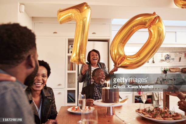 female with number 70 balloons at birthday party - küche überrascht mann stock-fotos und bilder