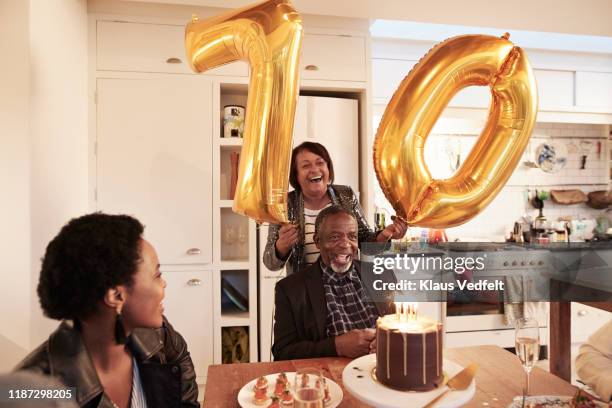 happy woman with number 70 balloons at birthday party - black balloon stock-fotos und bilder