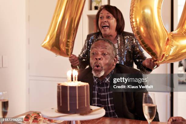 man blowing candles on cake during birthday party - lifestyle moments stockfoto's en -beelden