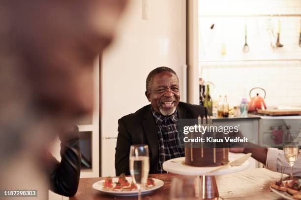 cheerful man enjoying birthday party at home - senior birthday stock pictures, royalty-free photos & images