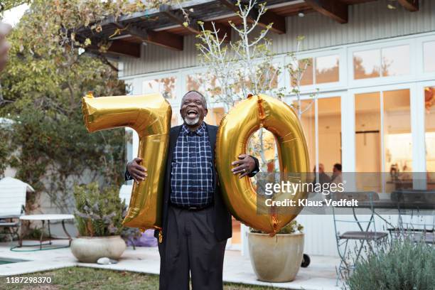 happy man with number 70 helium balloons in backyard - black balloons stock pictures, royalty-free photos & images