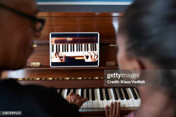 grandmother teaching piano to grandchild - children interacting with tablet technology stock pictures, royalty-free photos & images