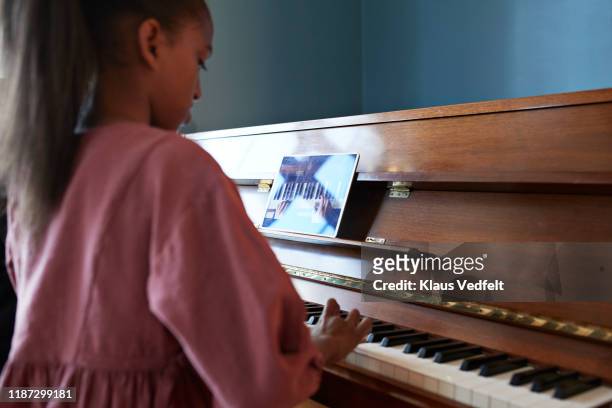 Grandmother teaching grand piano to granddaughter