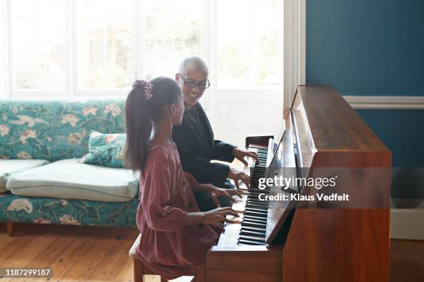 woman teaching piano to granddaughter - black granny stock pictures, royalty-free photos & images