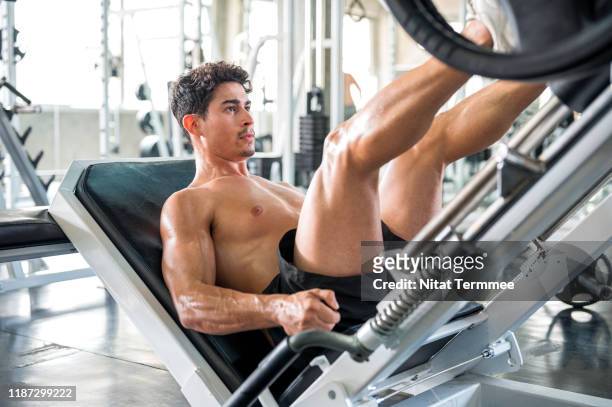 healthy lifestyle, exercising and people concepts. muscular man doing leg presses on leg press machine in the gym. - legs stockfoto's en -beelden