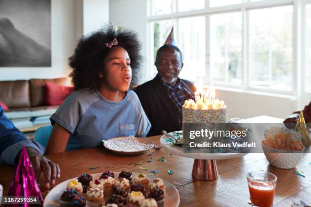 girl blowing candles during birthday celebration - cupcakes girls fotografías e imágenes de stock