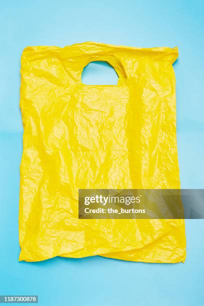 directly above shot of yellow plastic bag on blue background - plastic bag stock-fotos und bilder