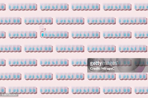neatly arranged pill organizers with blue capsules - pilulier photos et images de collection