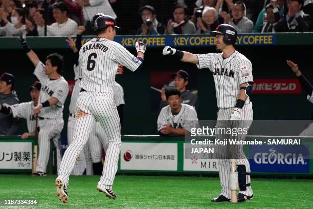 Infielder Hayato Sakamoto of Japan celebrates with Infielder Shuta Tonosaki after scoring a run by a RBI single of Outfielder Seiya Suzuki in the...