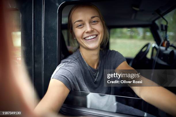 portrait of a happy young woman in an off-road vehicle - selfi stock-fotos und bilder