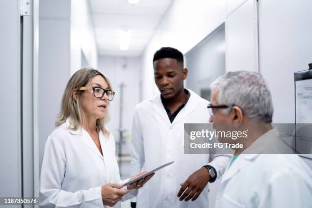 colleagues working and using digital tablet in laboratory - medical research group stock pictures, royalty-free photos & images