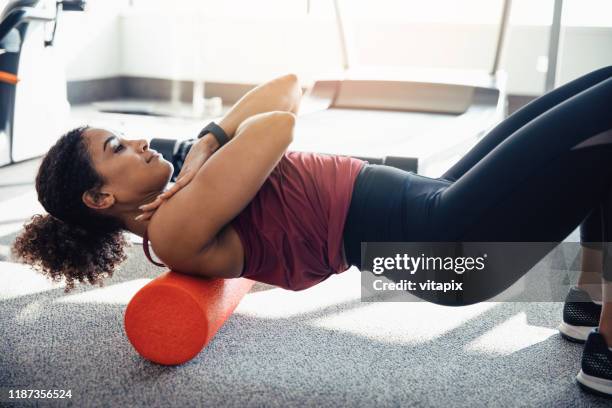 stretching her upper back - black woman gym clothing stock pictures, royalty-free photos & images