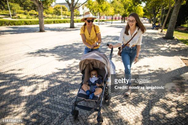 ung mamma och hennes vän på en promenad med pojke under vacker dag i lissabon - baby pram in the park bildbanksfoton och bilder