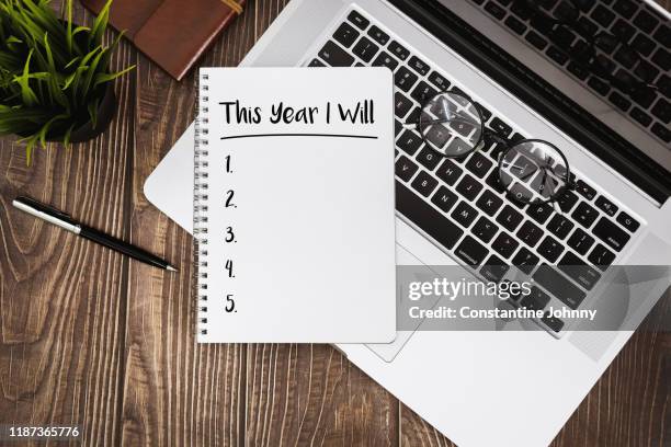 new year resolutions on notebook with laptop over wood desk. - neujahrsvorsatz stock-fotos und bilder