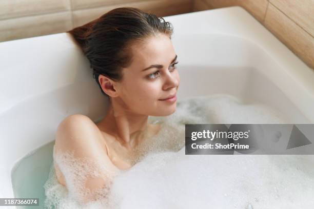 a woman lies in a bubble bath and looks out the window - woman bath bubbles stock-fotos und bilder