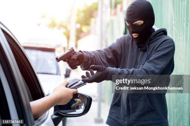 car thief pointing a gun at the driver - kidnapping imagens e fotografias de stock