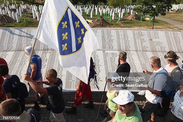 Peace marchers bearing the flag of Muslim Bosnia walk past a stone memorial bearing the names of victims of the 1995 Srebrenica massacre at the...