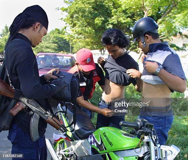Indonesian police in civilian clothes check two students at Tungkop village in Banda Aceh, 09 July 2003. According to the latest military figures,...