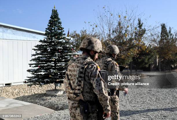 December 2019, Afghanistan, Kundus: Soldiers walk past a decorated Christmas tree at Camp Pamir in Kunduz. Photo: Britta Pedersen/dpa-Zentralbild/ZB