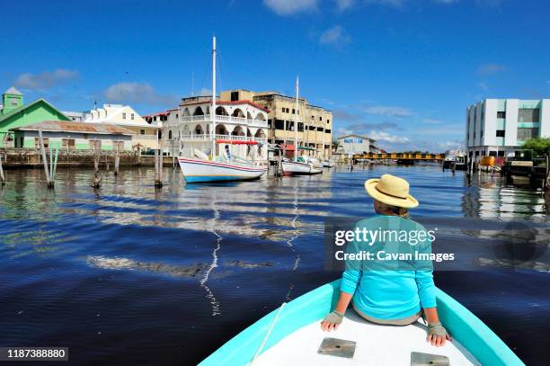 a woman tours through belize city on the bow of a fishing boat - belize stock pictures, royalty-free photos & images