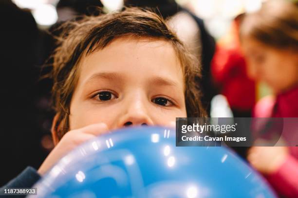 boy blowing balloon - inflar fotografías e imágenes de stock