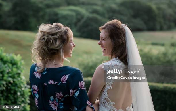 bride and her friend holding hands laughing on her wedding day - mariage stock pictures, royalty-free photos & images