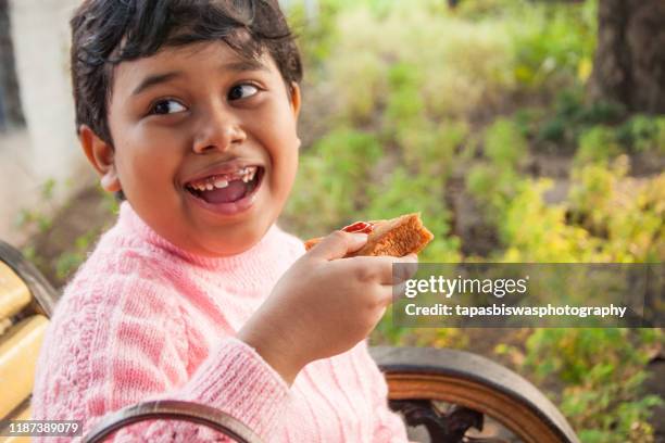 smiling girl eating sandwich - bengali girl stock-fotos und bilder