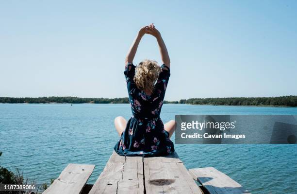 woman stretching whilst meditating in front of the sea - lake finland bildbanksfoton och bilder
