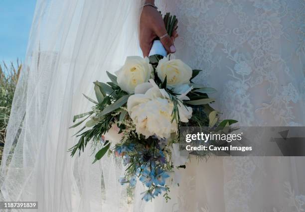 bride standing in her lace wedding dress holding her bouque of flowers - adult eating no face stock pictures, royalty-free photos & images