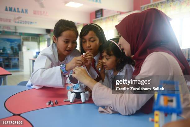 asian elementary schoolgirls and female teacher building robot in science class - malaysia school stock pictures, royalty-free photos & images