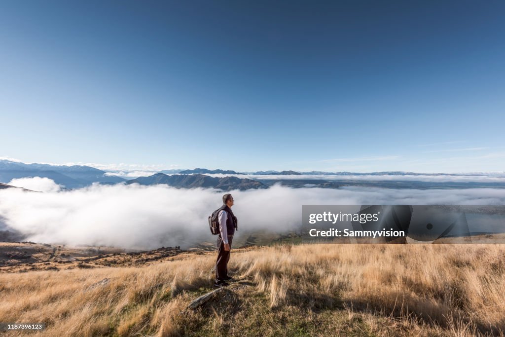 Senior man hiking on the mountain against the dramatic cloudscape