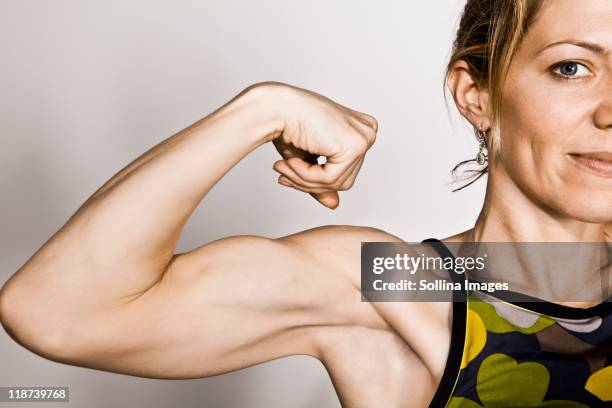 blond woman flexes bicep - flexionar los músculos fotografías e imágenes de stock