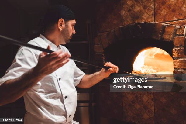pizza maker glidande pizza av en skal i en vedeldad ugn - pizzeria bildbanksfoton och bilder