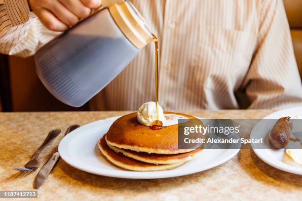 man pouring maple syrup over pancakes in the diner - american pancakes stock pictures, royalty-free photos & images