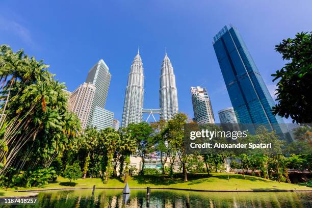 petronas towers and park with a lake on a sunny day, kuala lumpur, malaysia - kuala lumpur landscape stock pictures, royalty-free photos & images