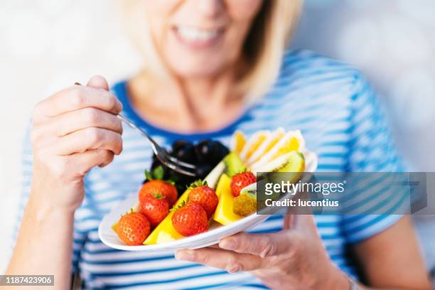 aantrekkelijke senior vrouw met fruit lunch - healthy snacks stockfoto's en -beelden