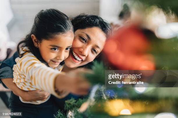 mother and daughter decorating christmas tree - tradition stock pictures, royalty-free photos & images