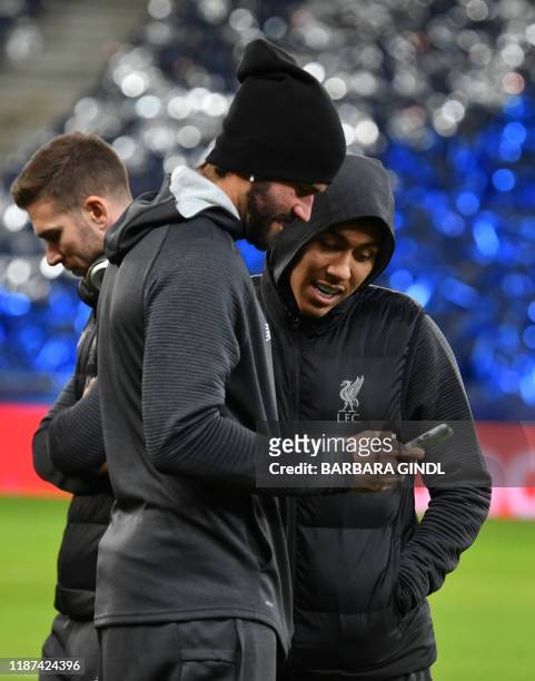 Liverpool's Brazilian goalkeeper Alisson Becker and Liverpool's Brazilian midfielder Roberto Firmino look at a smartphone during a place inspection...