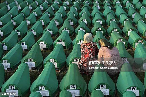 Two young Muslim women mourn over a coffin among 613 coffins of victims of the 1995 Srebrenica massacre laid out on a lawn at the Potocari cemetery...