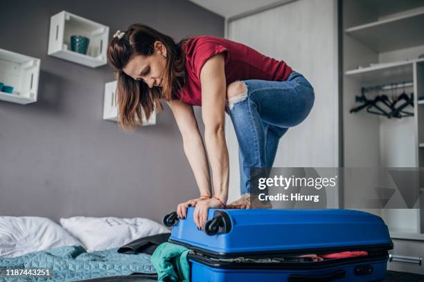 donna che cerca di impacchettare troppo valigia vicina - suitcase close foto e immagini stock