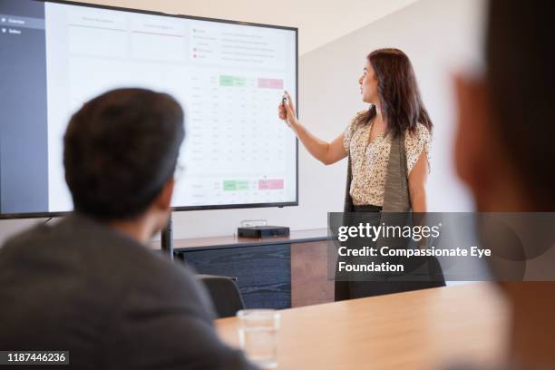 businesswoman using graphs on screen in business meeting - vanguardista imagens e fotografias de stock