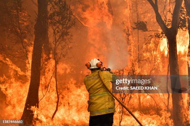 Firefighter conducts back-burning measures to secure residential areas from encroaching bushfires in the Central Coast, some 90-110 kilometres north...