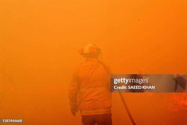 Firefighter conducts back-burning measures to secure residential areas from encroaching bushfires in the Central Coast, some 90-110 kilometres north...