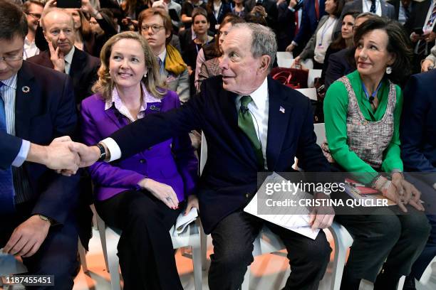 Democratic presidential hopeful Michael Bloomberg sits between Spanish Santander Bank executive chairperson Ana Botin and Spanish careteker minister...