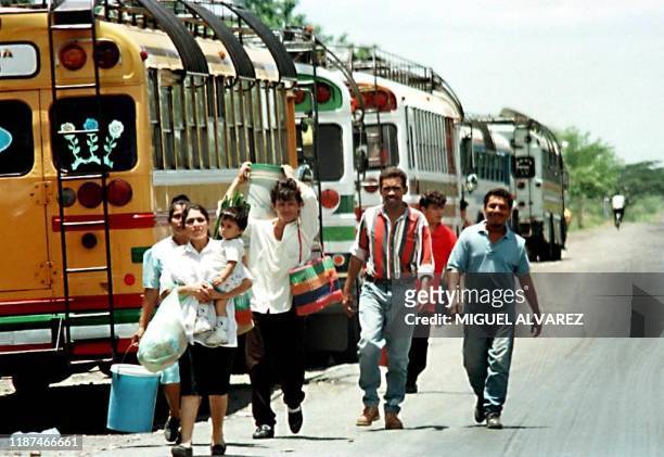 Un grupo de ciudadanos caminan al lado de cientos de buses que permanecen en paro desde hace 48 horas a orillas de la carretera Panamericana, en la...