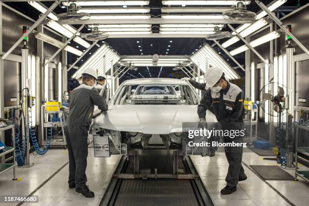 Workers clean the hood of a body frame of a Vinfast Lux A2.0 sedan in the body shop area of the automaker's factory in Haiphong, Vietnam, on...