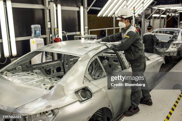 Worker cleans the top of a body frame of a Vinfast Lux A2.0 sedan in the body shop area of the automaker's factory in Haiphong, Vietnam, on...