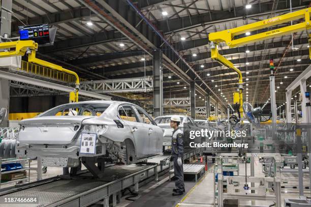 Worker checks the body frame of a Vinfast Lux A2.0 sedan as it moves along a conveyor in the body shop area of the automaker's factory in Haiphong,...