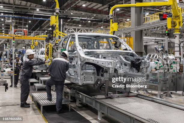 Workers attach a rear door to the body frame of a Vinfast Lux A2.0 sedan as it moves along a conveyor in the body shop area of the automaker's...