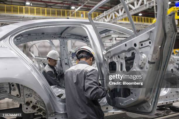 Workers attach rear doors to the body frame of a Vinfast Lux A2.0 sedan as it moves along a conveyor in the body shop area of the automaker's factory...